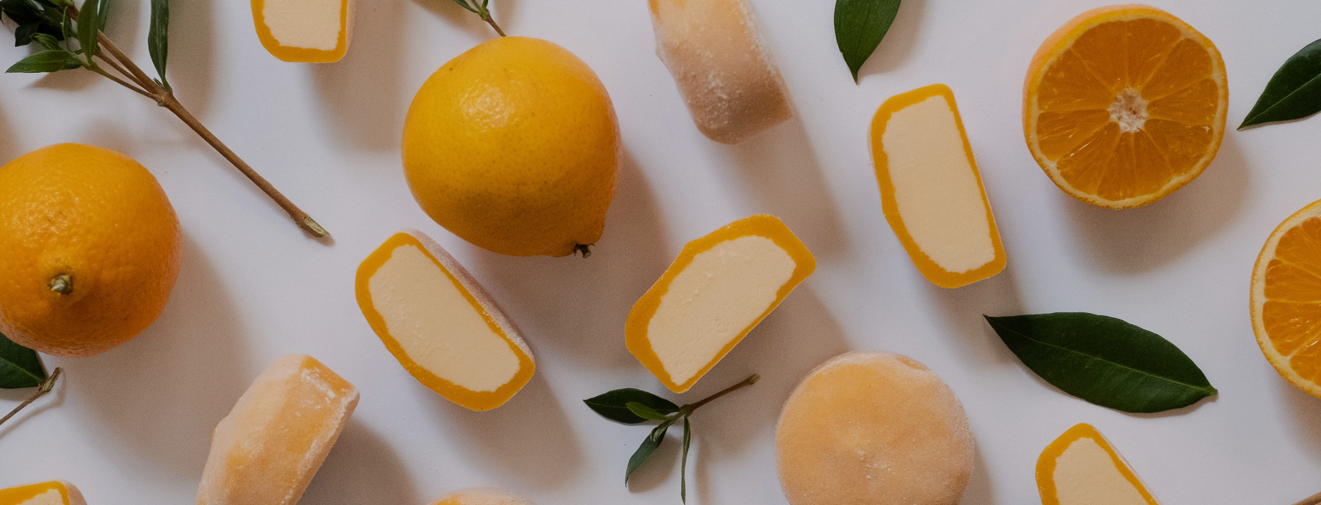 Mochidoki Loyalty Program banner: Flat-lay of whole and halved oranges, green leaves, and orange‑shelled ice cream pieces on a white background.