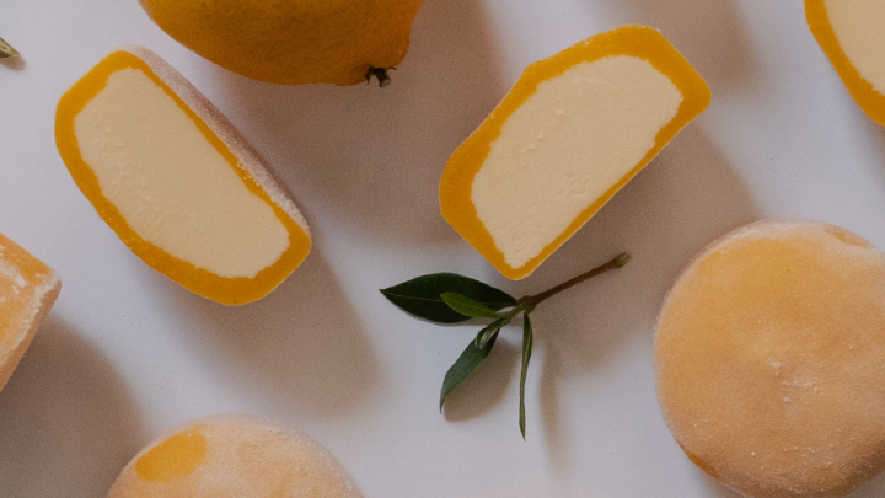 Mochidoki Loyalty Program banner (mobile): Flat-lay of whole and halved oranges, green leaves, and orange‑shelled ice cream pieces on a white background.